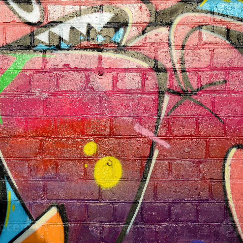 Abstract colorful fragment of graffiti paintings on old brick wall. Street art composition with parts of unwritten letters and multicolored stains. Subcultural background texture photo