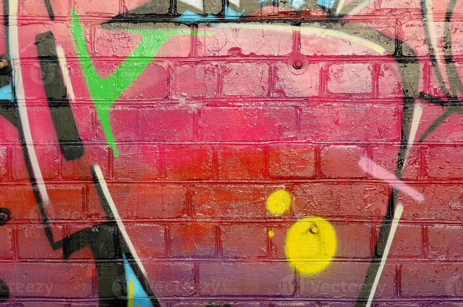 Abstract colorful fragment of graffiti paintings on old brick wall. Street-art composition with parts of wild letters and multicolored stains. Subcultural background texture photo