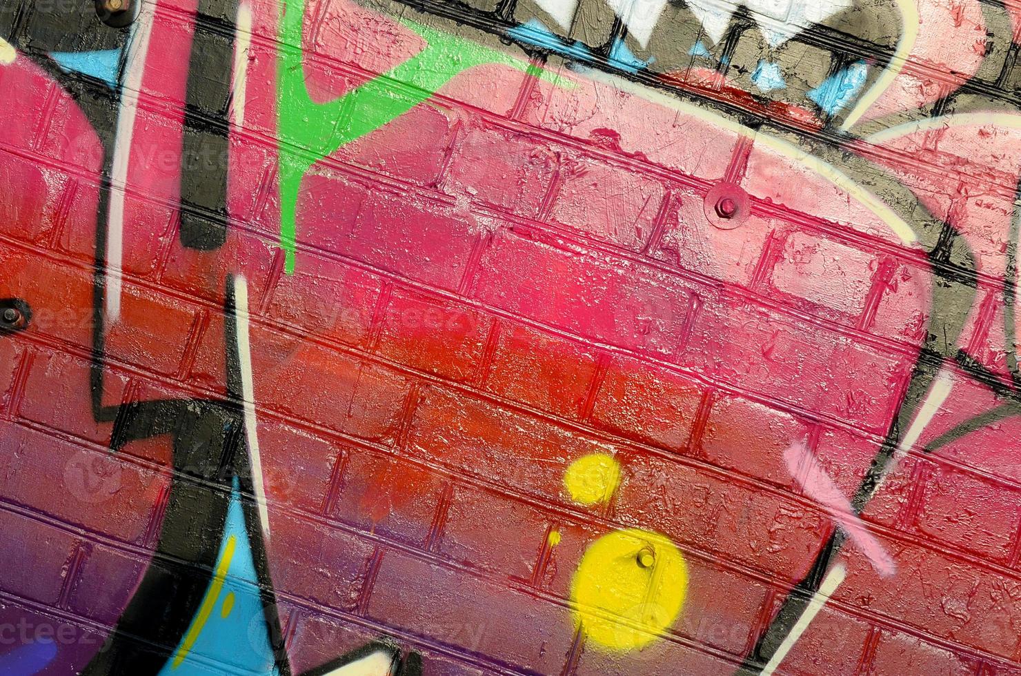 Abstract colorful fragment of graffiti paintings on old brick wall. Street-art composition with parts of wild letters and multicolored stains. Subcultural background texture photo