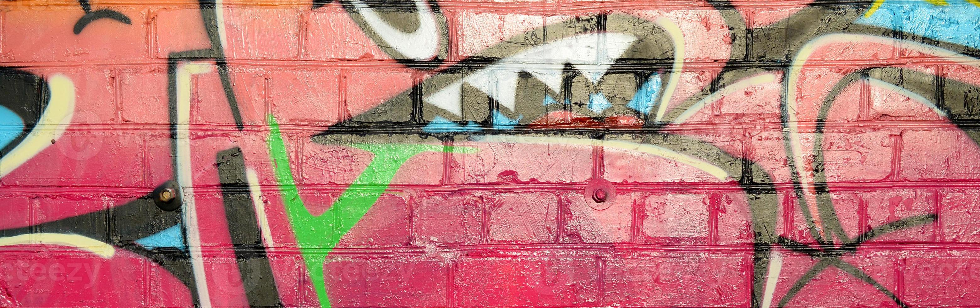 Abstract colorful fragment of graffiti paintings on old brick wall. Street-art composition with parts of wild letters and multicolored stains. Subcultural background texture photo