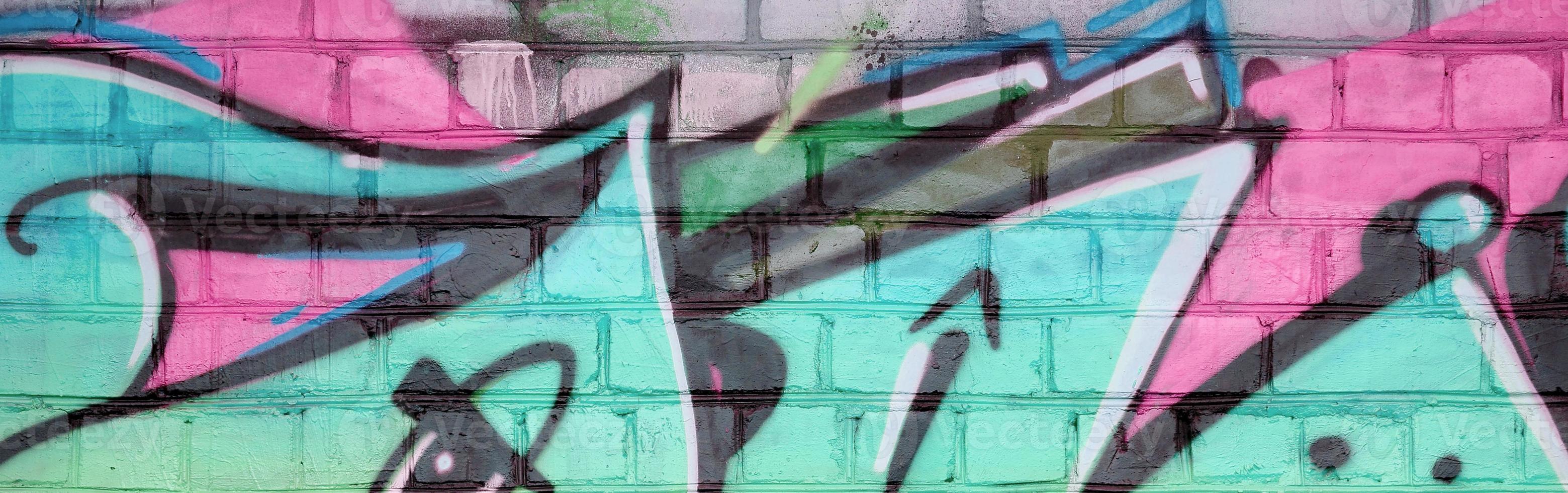 Abstract colorful fragment of graffiti paintings on old brick wall in pink and green colors. Street art composition with parts of unwritten letters and multicolored stains photo