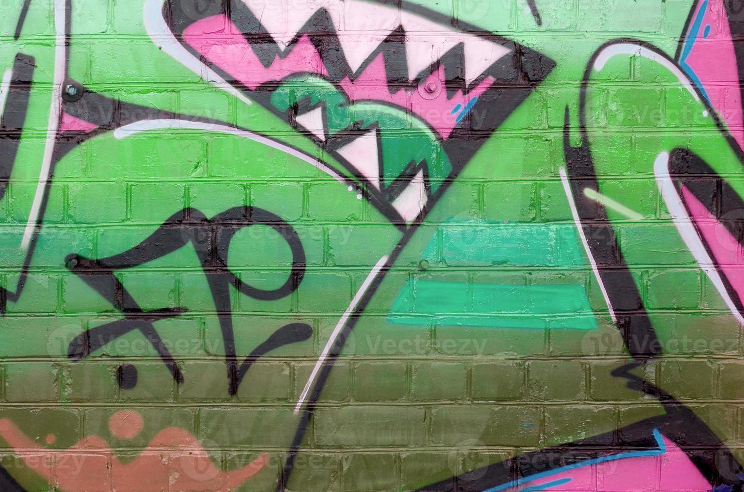 Abstract colorful fragment of graffiti paintings on old brick wall in pink and green colors. Street art composition with parts of unwritten letters and multicolored stains photo