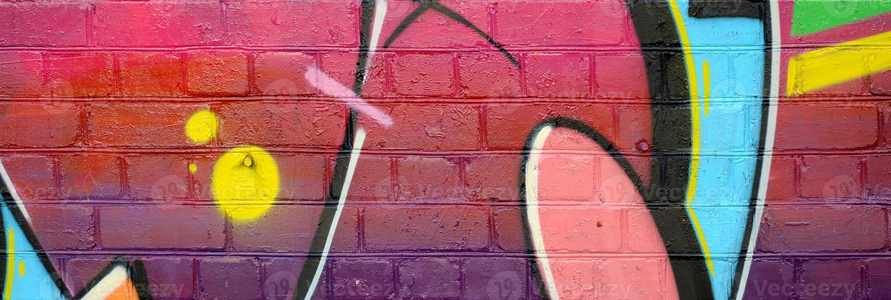 Abstract colorful fragment of graffiti paintings on old brick wall. Street-art composition with parts of wild letters and multicolored stains. Subcultural background texture photo