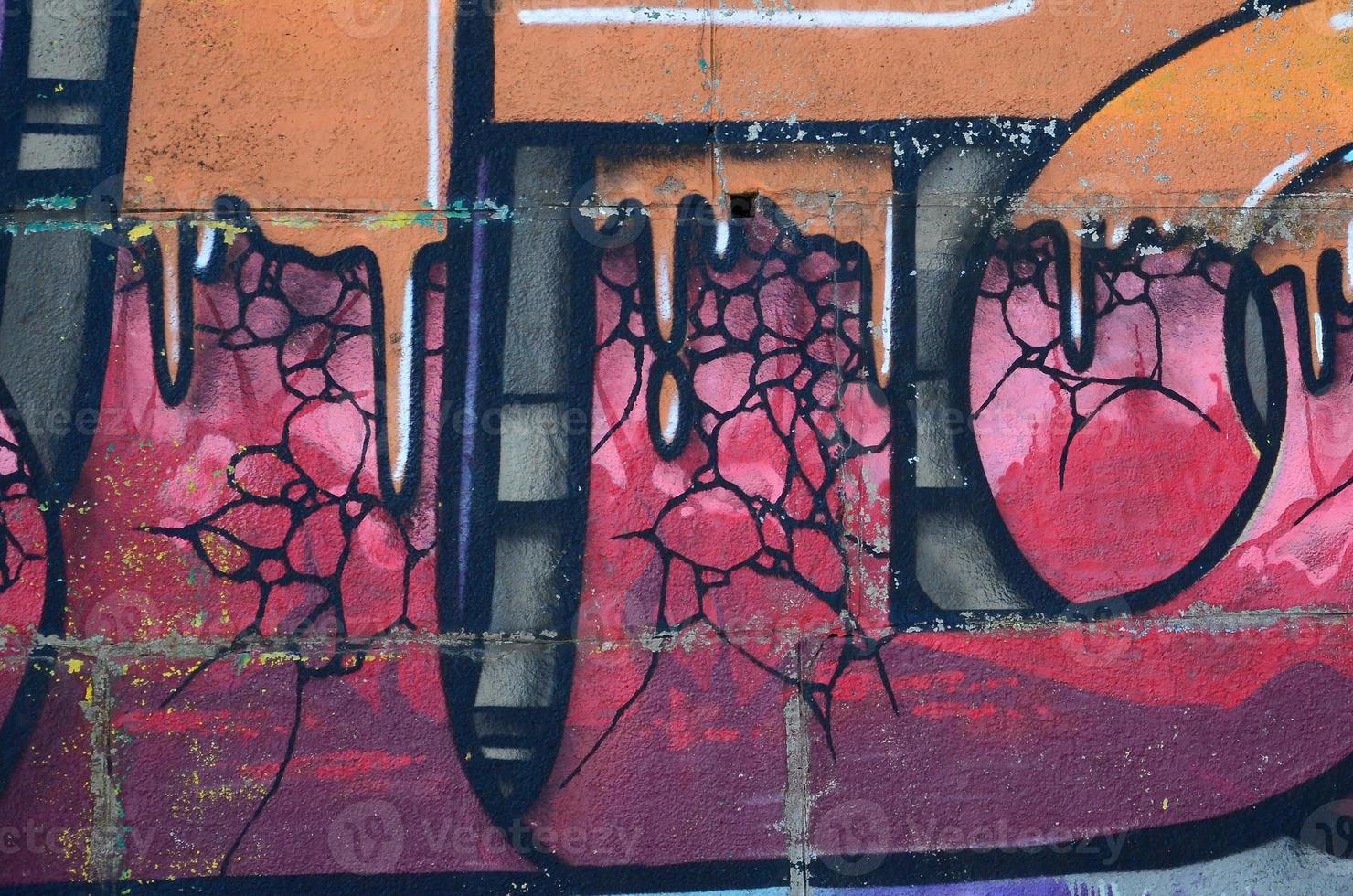 Fragment of graffiti drawings. The old wall decorated with paint stains in the style of street art culture. Colored background texture in warm tones photo