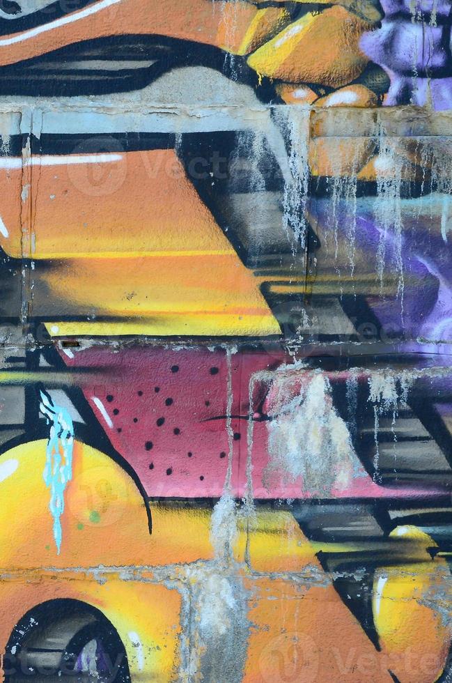 Fragment of graffiti drawings. The old wall decorated with paint stains in the style of street art culture. Colored background texture in warm tones photo