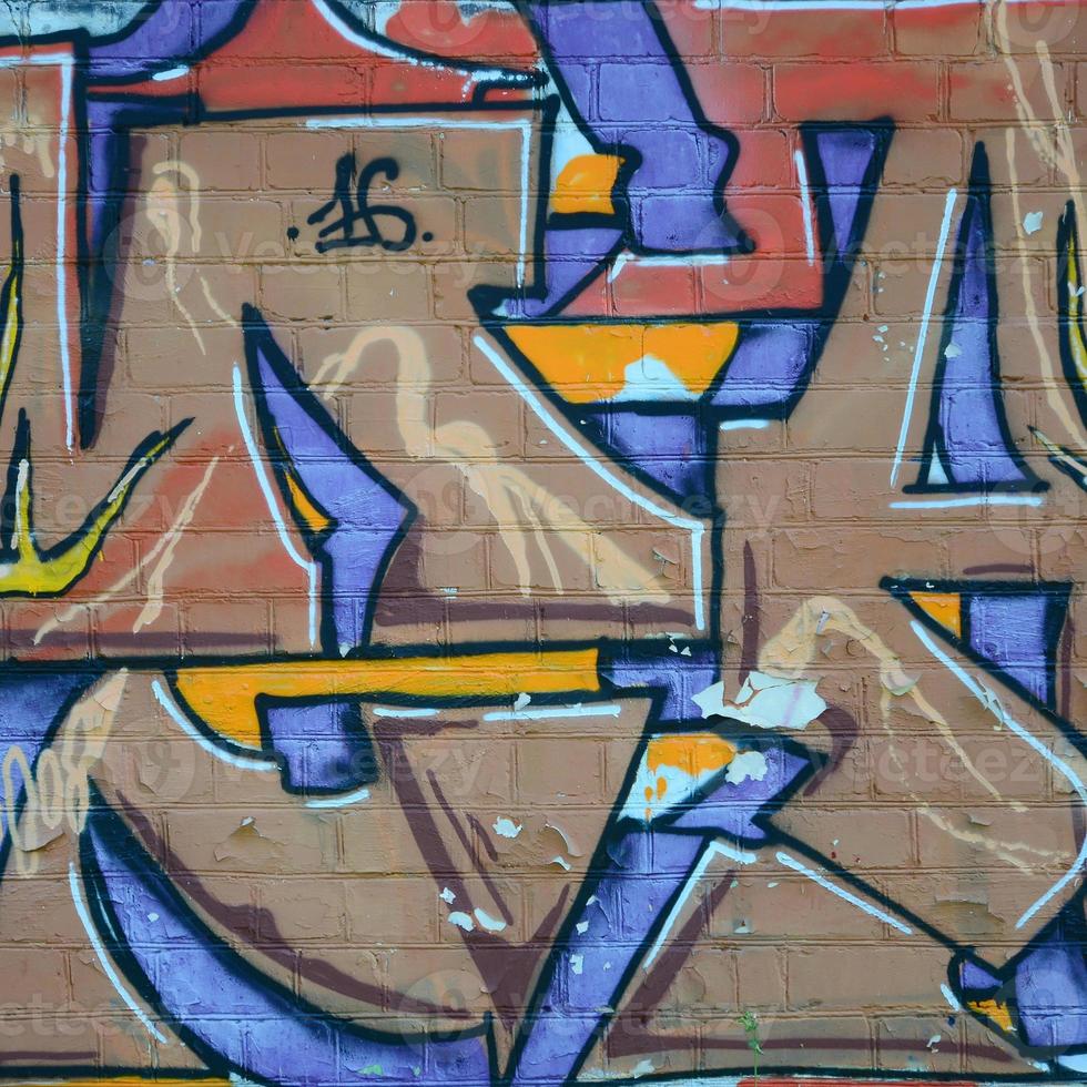 Fragment of graffiti drawings. The old wall decorated with paint stains in the style of street art culture. Colored background texture in warm tones photo