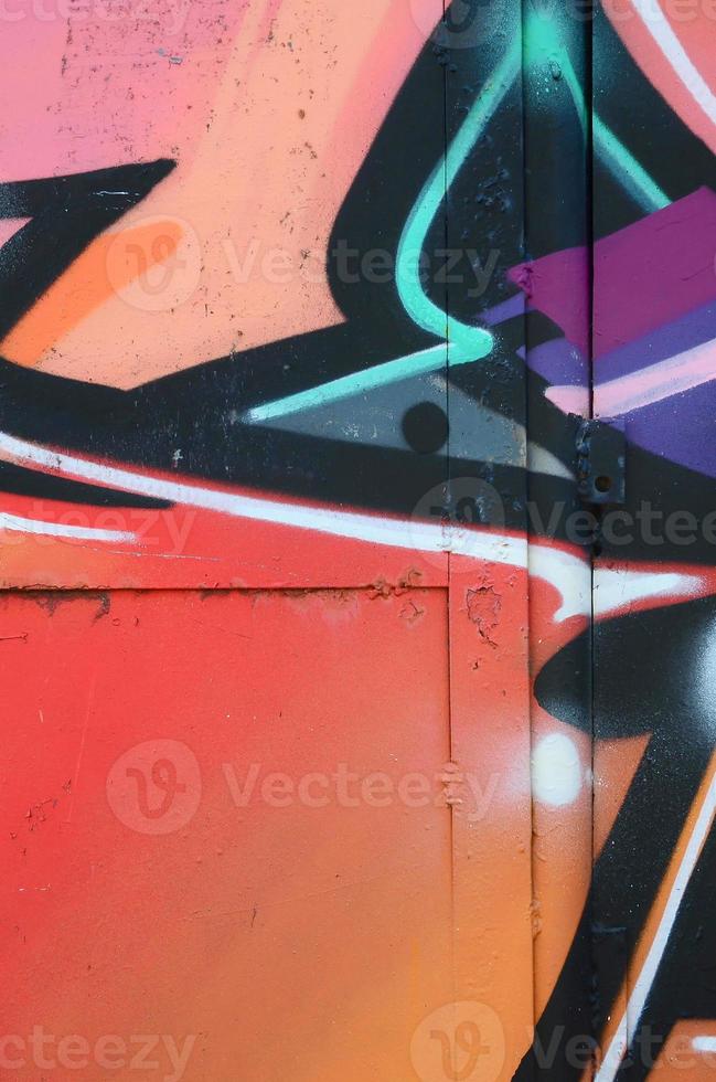 Fragment of graffiti drawings. The old wall decorated with paint stains in the style of street art culture. Colored background texture in warm tones photo