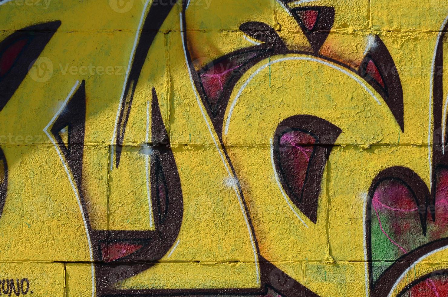 Fragment of graffiti drawings. The old wall decorated with paint stains in the style of street art culture. Colored background texture in warm tones photo