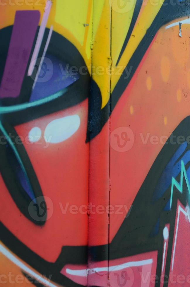 Fragment of graffiti drawings. The old wall decorated with paint stains in the style of street art culture. Colored background texture in warm tones photo