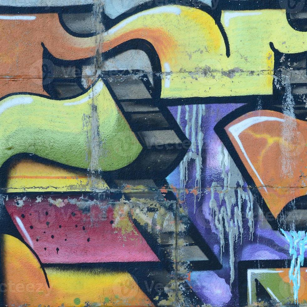 Fragment of graffiti drawings. The old wall decorated with paint stains in the style of street art culture. Colored background texture in warm tones photo
