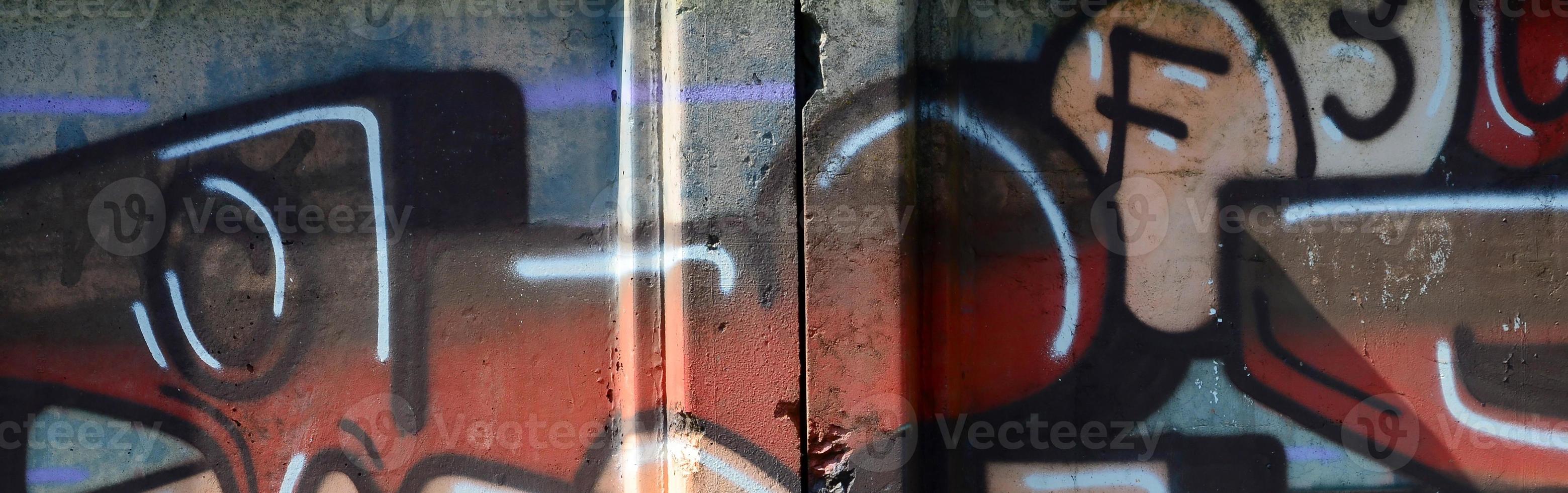 Fragment of graffiti drawings. The old wall decorated with paint stains in the style of street art culture. Colored background texture in warm tones photo