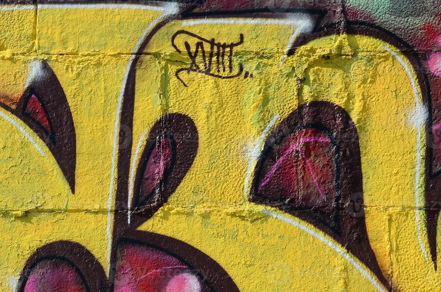Fragment of graffiti drawings. The old wall decorated with paint stains in the style of street art culture. Colored background texture in warm tones photo