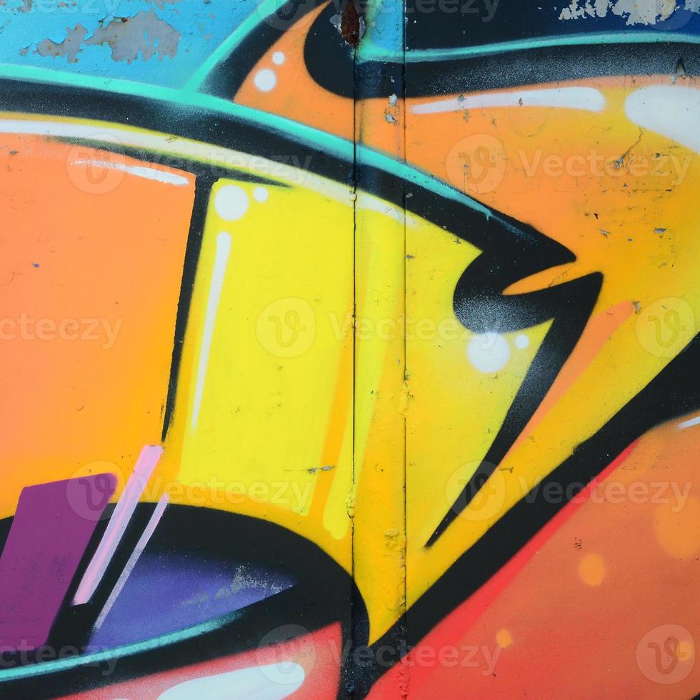 Fragment of graffiti drawings. The old wall decorated with paint stains in the style of street art culture. Colored background texture in warm tones photo