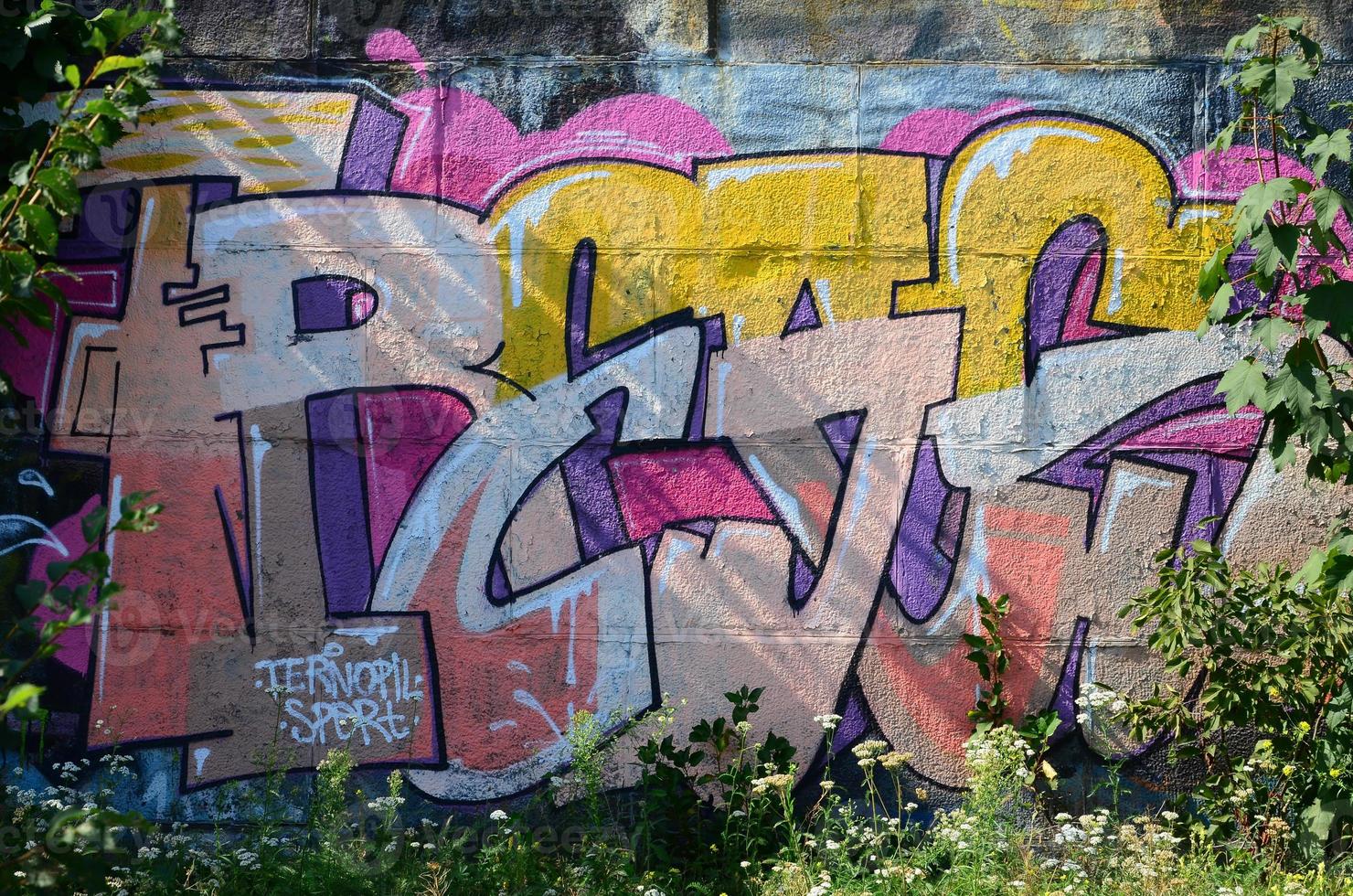 Fragment of graffiti drawings. The old wall decorated with paint stains in the style of street art culture. Colored background texture in warm tones photo