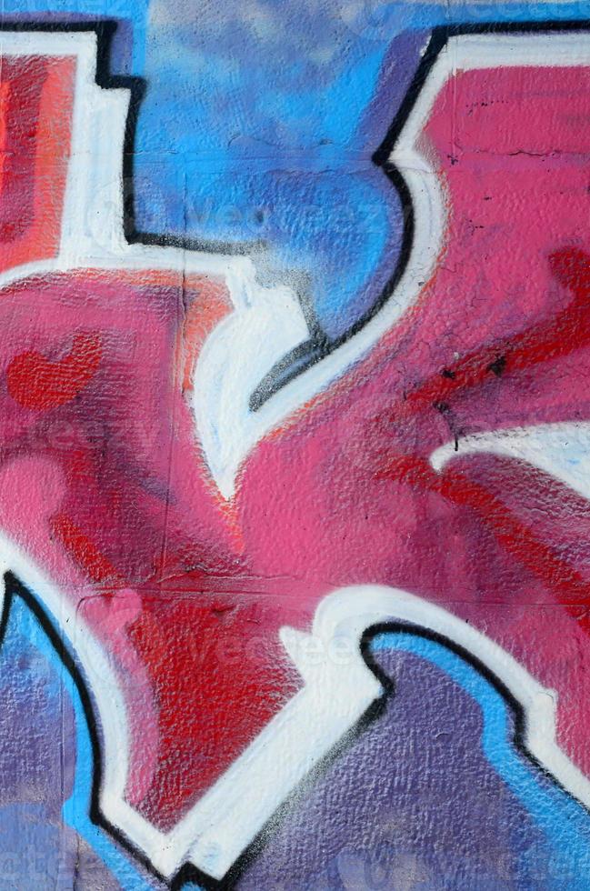 Fragment of graffiti drawings. The old wall decorated with paint stains in the style of street art culture. Colored background texture in warm tones photo