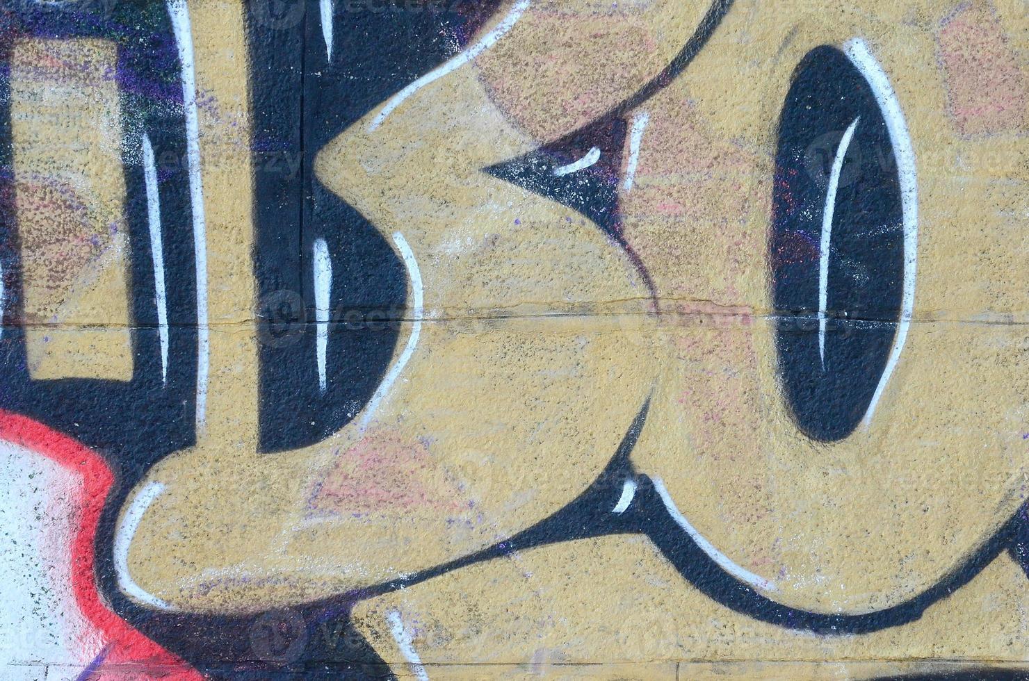 Fragment of graffiti drawings. The old wall decorated with paint stains in the style of street art culture. Colored background texture in warm tones photo