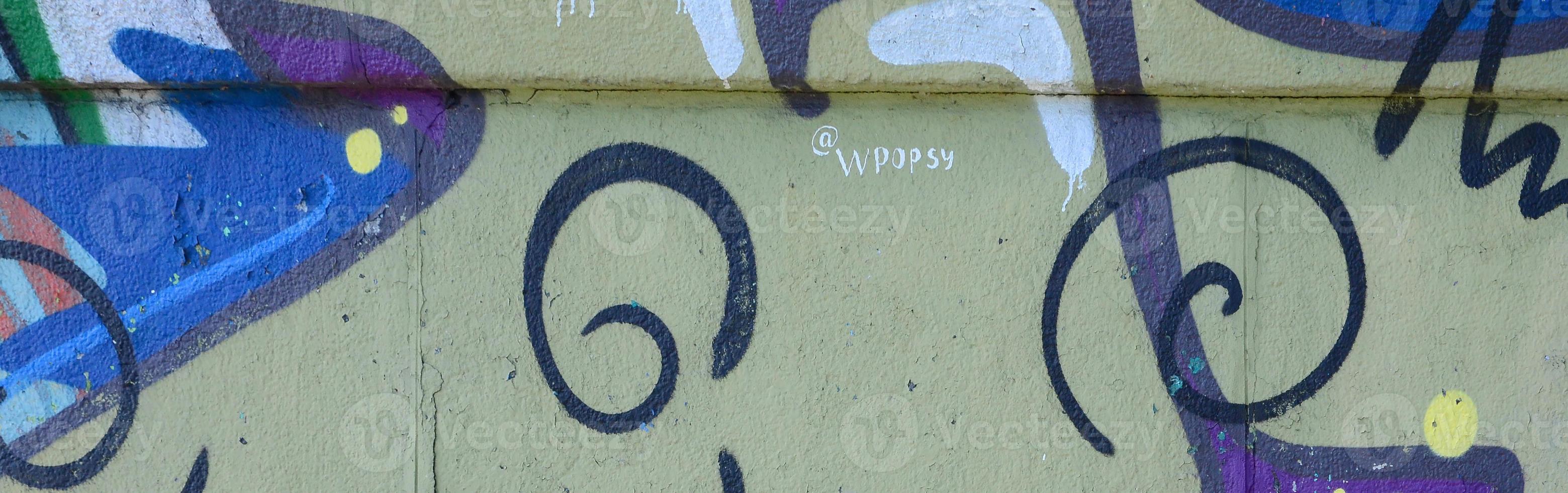 Fragment of graffiti drawings. The old wall decorated with paint stains in the style of street art culture. Colored background texture in warm tones photo