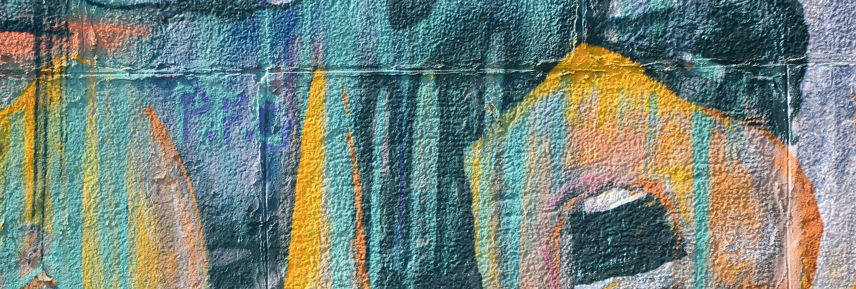 Fragment of graffiti drawings. The old wall decorated with paint stains in the style of street art culture. Colored background texture in warm tones photo