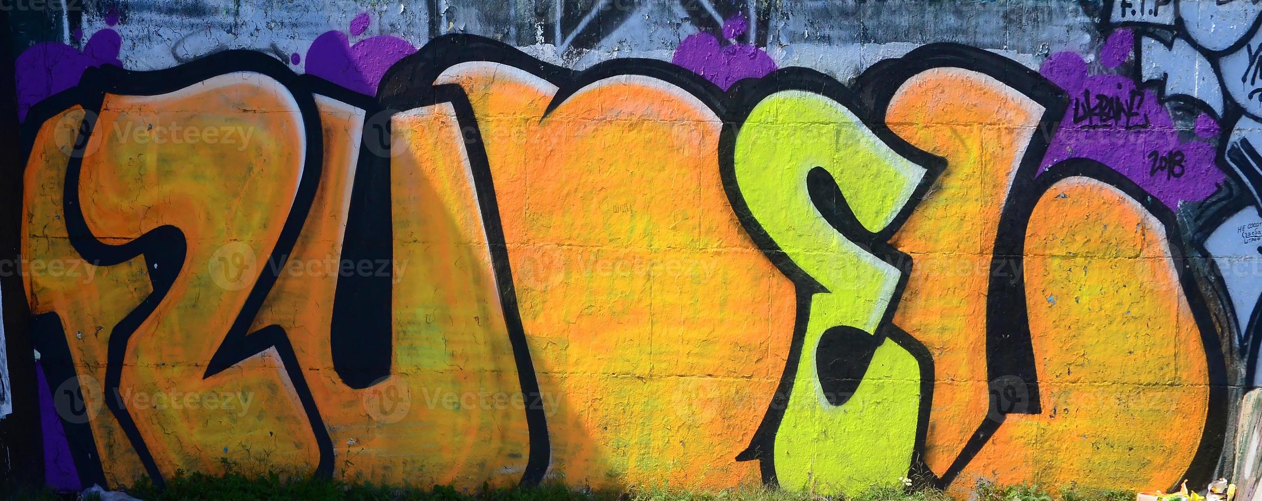 Fragment of graffiti drawings. The old wall decorated with paint stains in the style of street art culture. Colored background texture in warm tones photo