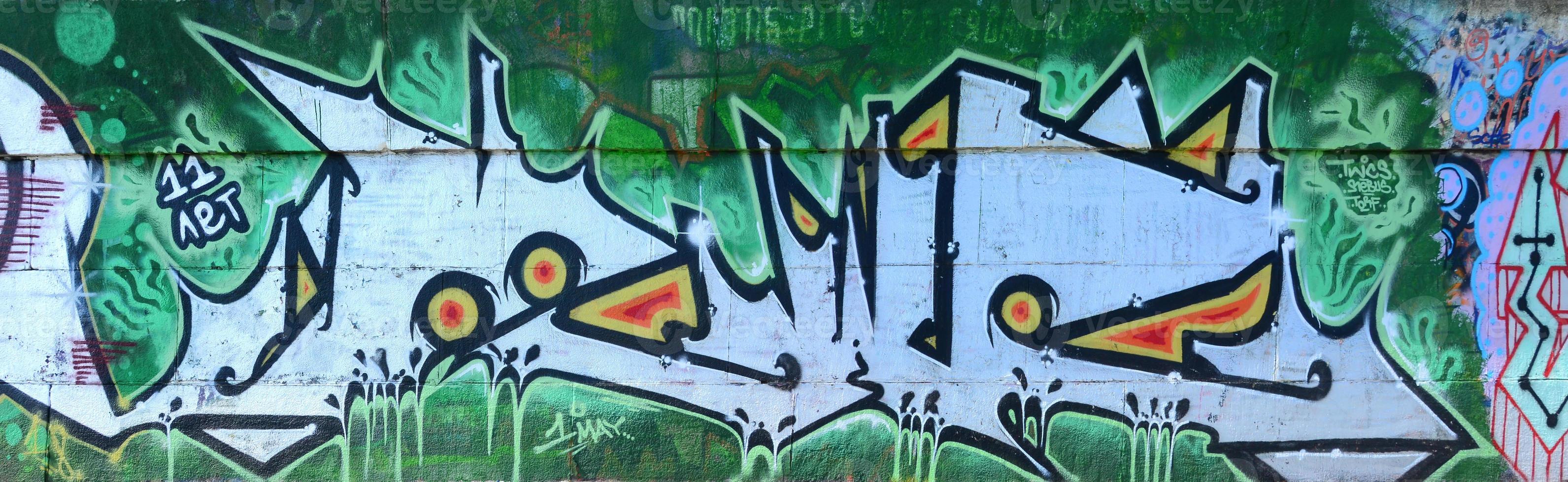 fragmento de dibujos de graffiti. la antigua muralla decorada con manchas de pintura al estilo de la cultura del arte callejero. textura de fondo coloreada en tonos verdes foto