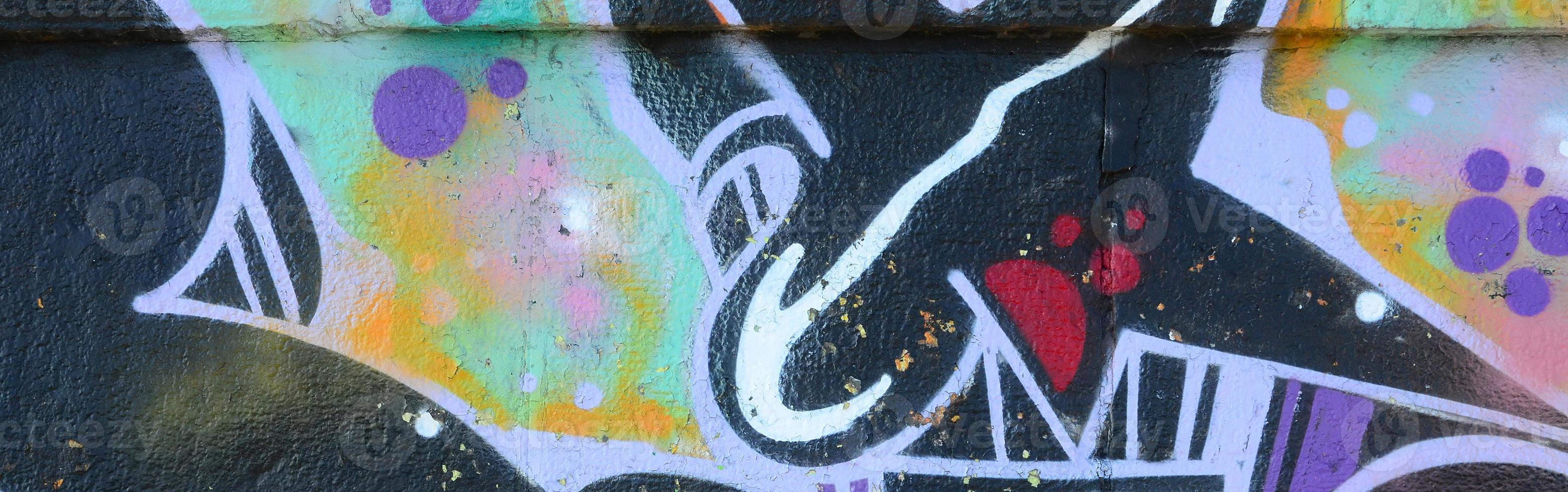 Fragment of graffiti drawings. The old wall decorated with paint stains in the style of street art culture. Colored background texture photo