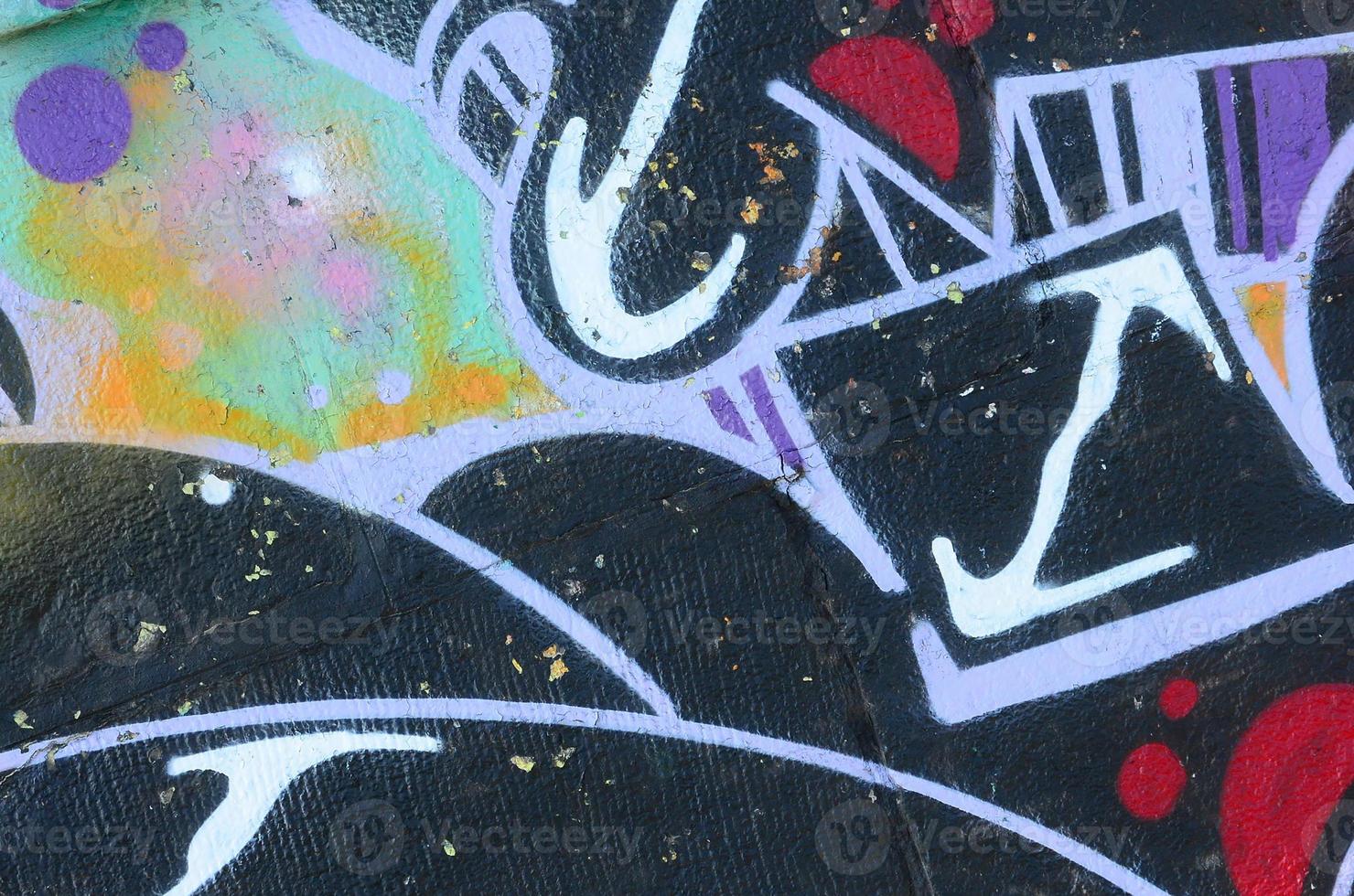 Fragment of graffiti drawings. The old wall decorated with paint stains in the style of street art culture. Colored background texture photo