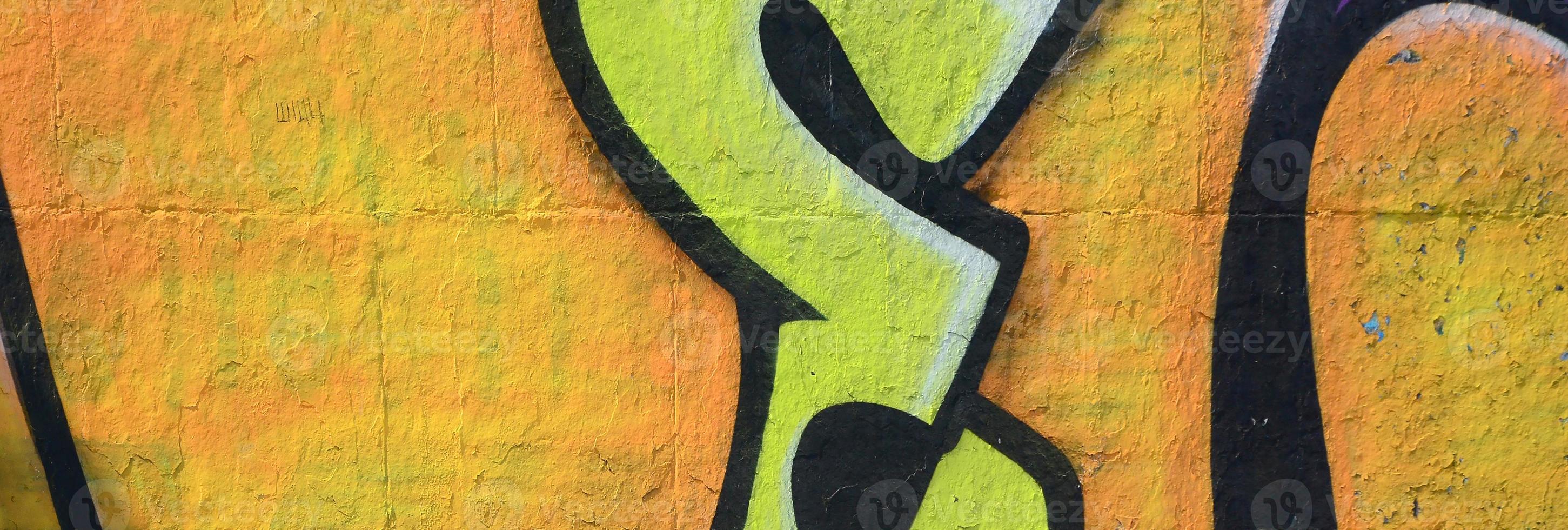 Fragment of graffiti drawings. The old wall decorated with paint stains in the style of street art culture. Colored background texture in warm tones photo