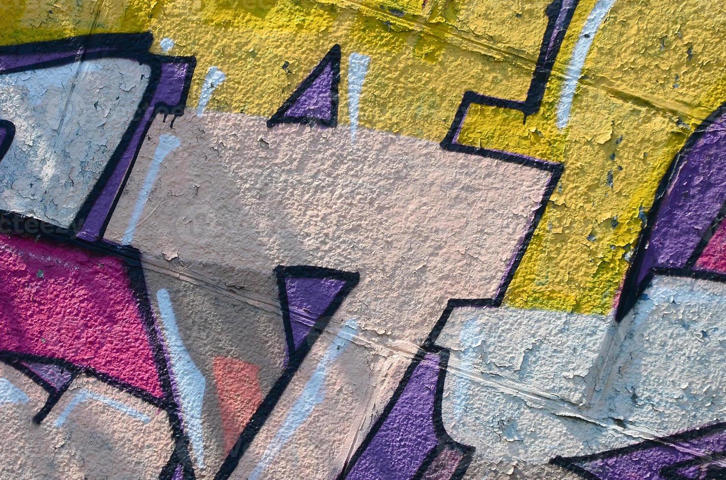 Fragment of graffiti drawings. The old wall decorated with paint stains in the style of street art culture. Colored background texture in warm tones photo