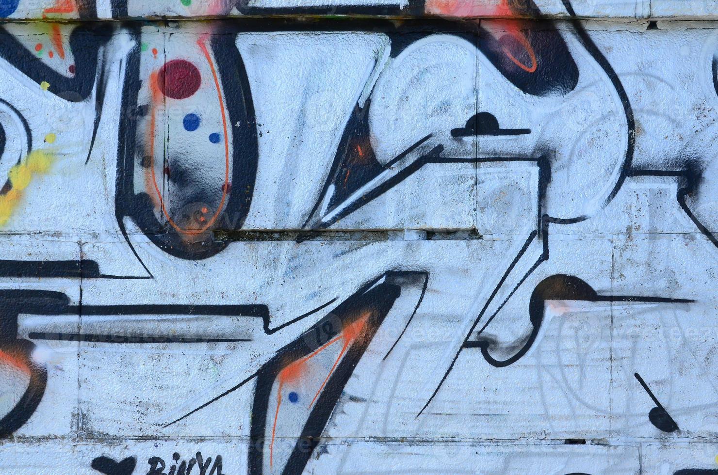 Fragment of graffiti drawings. The old wall decorated with paint stains in the style of street art culture. Colored background texture photo