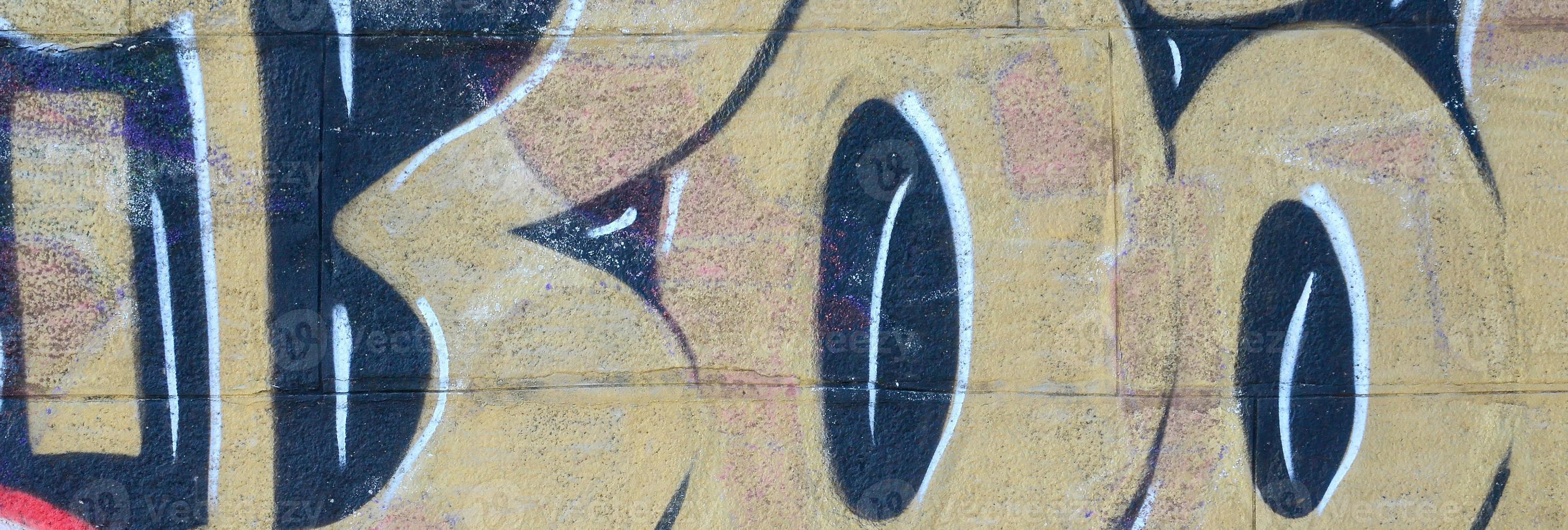 Fragment of graffiti drawings. The old wall decorated with paint stains in the style of street art culture. Colored background texture in warm tones photo