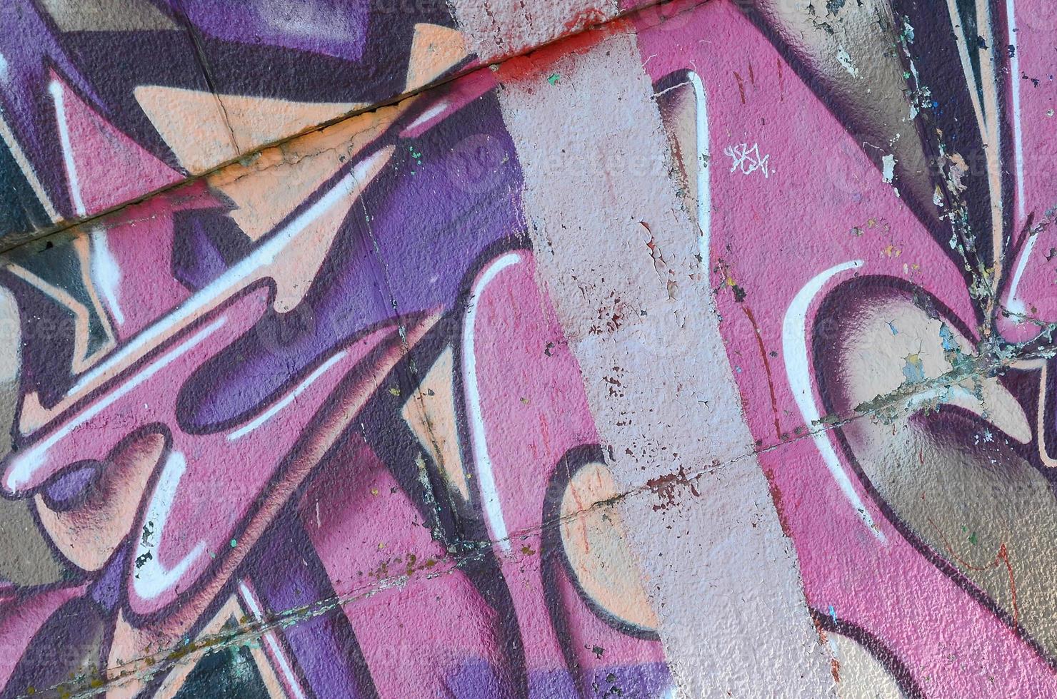 fragmento de dibujos de graffiti. la antigua muralla decorada con manchas de pintura al estilo de la cultura del arte callejero. textura de fondo coloreada en tonos morados foto