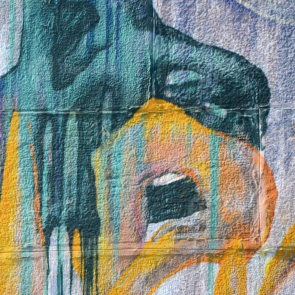 Fragment of graffiti drawings. The old wall decorated with paint stains in the style of street art culture. Colored background texture in warm tones photo