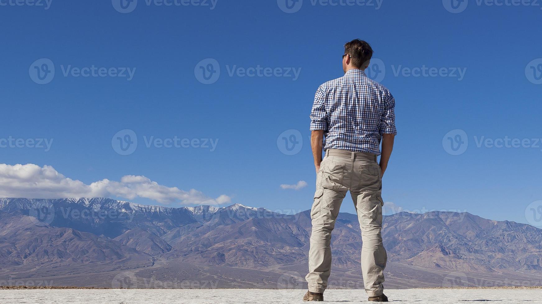 Shot of man from behind against imposing mountain backdrop photo