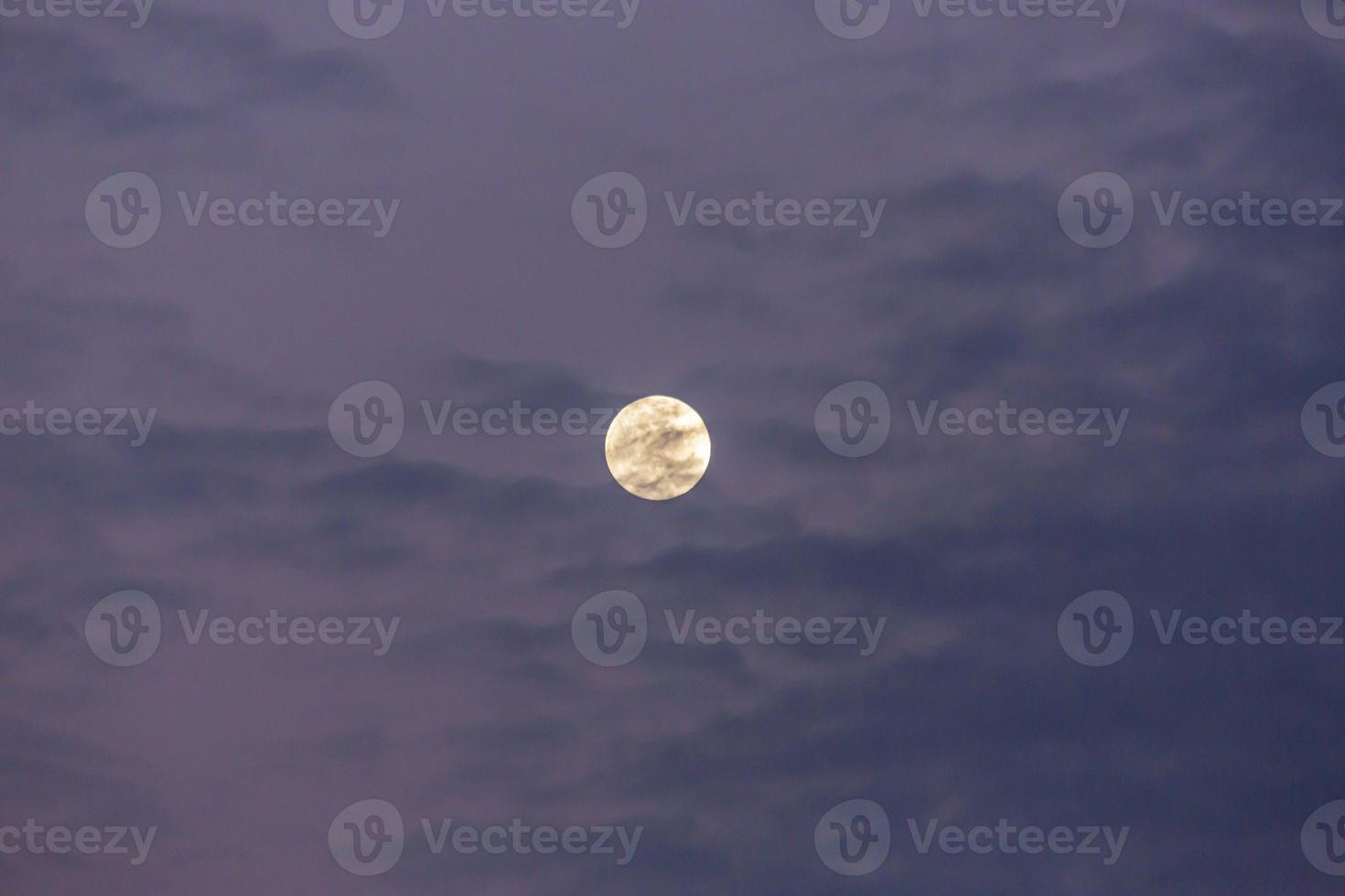 imagen de luna llena contra el colorido cielo nocturno con nubes claras foto