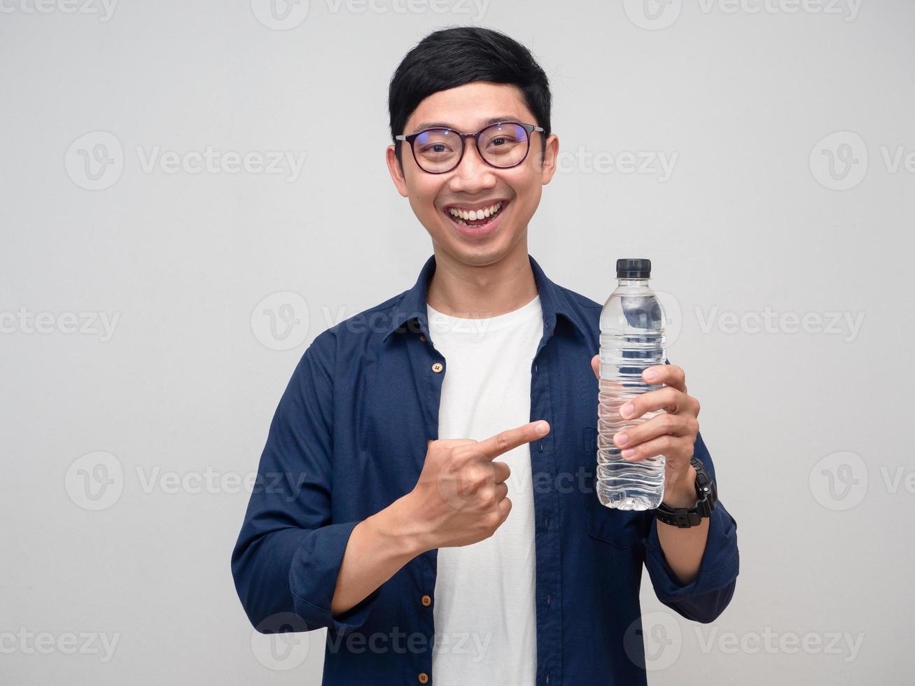 Positive man wear glasses gentle smile point finger at water bottle isolated photo