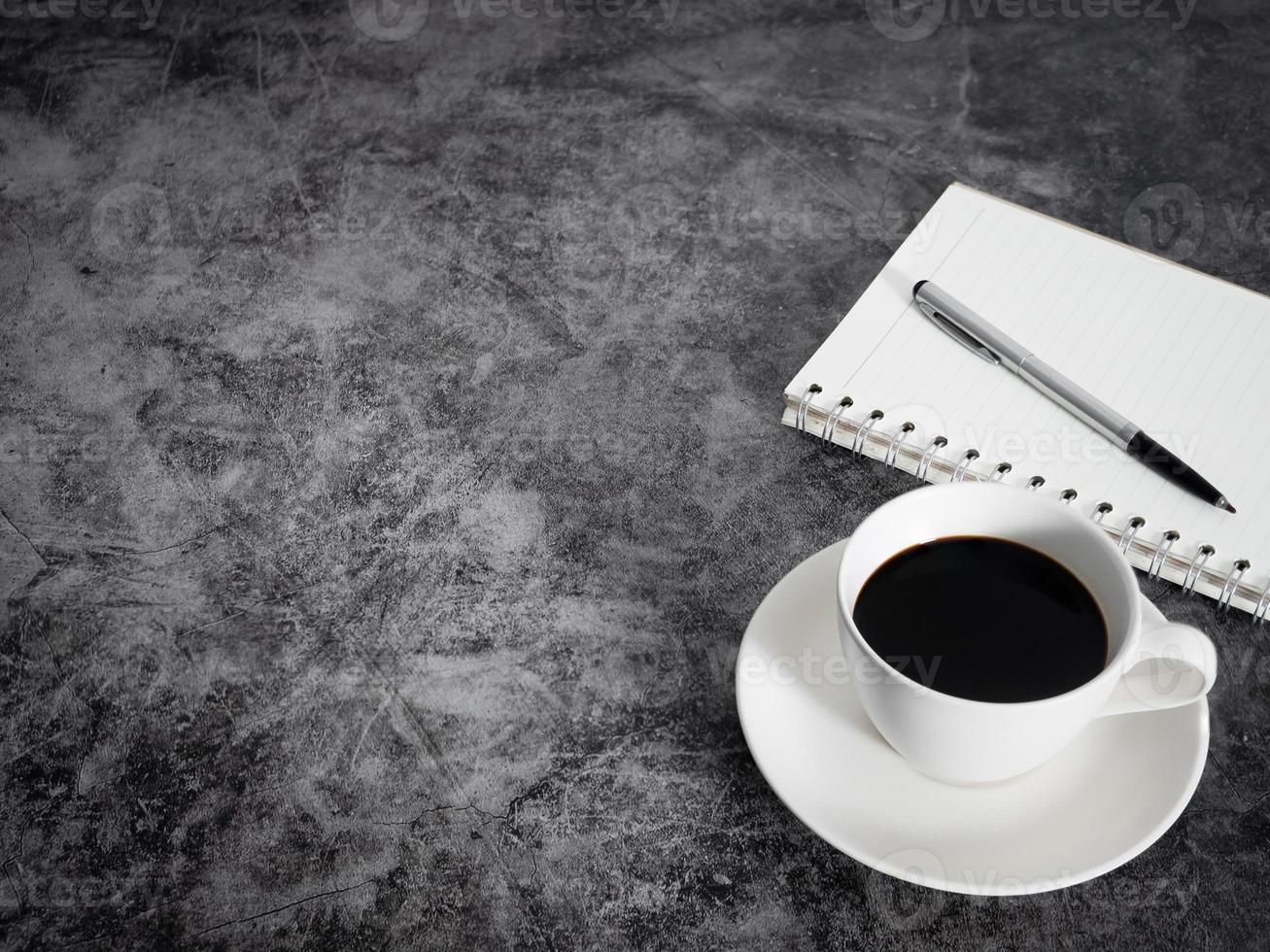 Black coffee white cup with notebook on dark floor table copy space top view photo