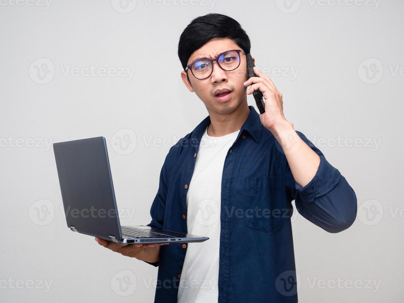 Asian businessman holding laptop with talking mobile busy and serious isolated photo