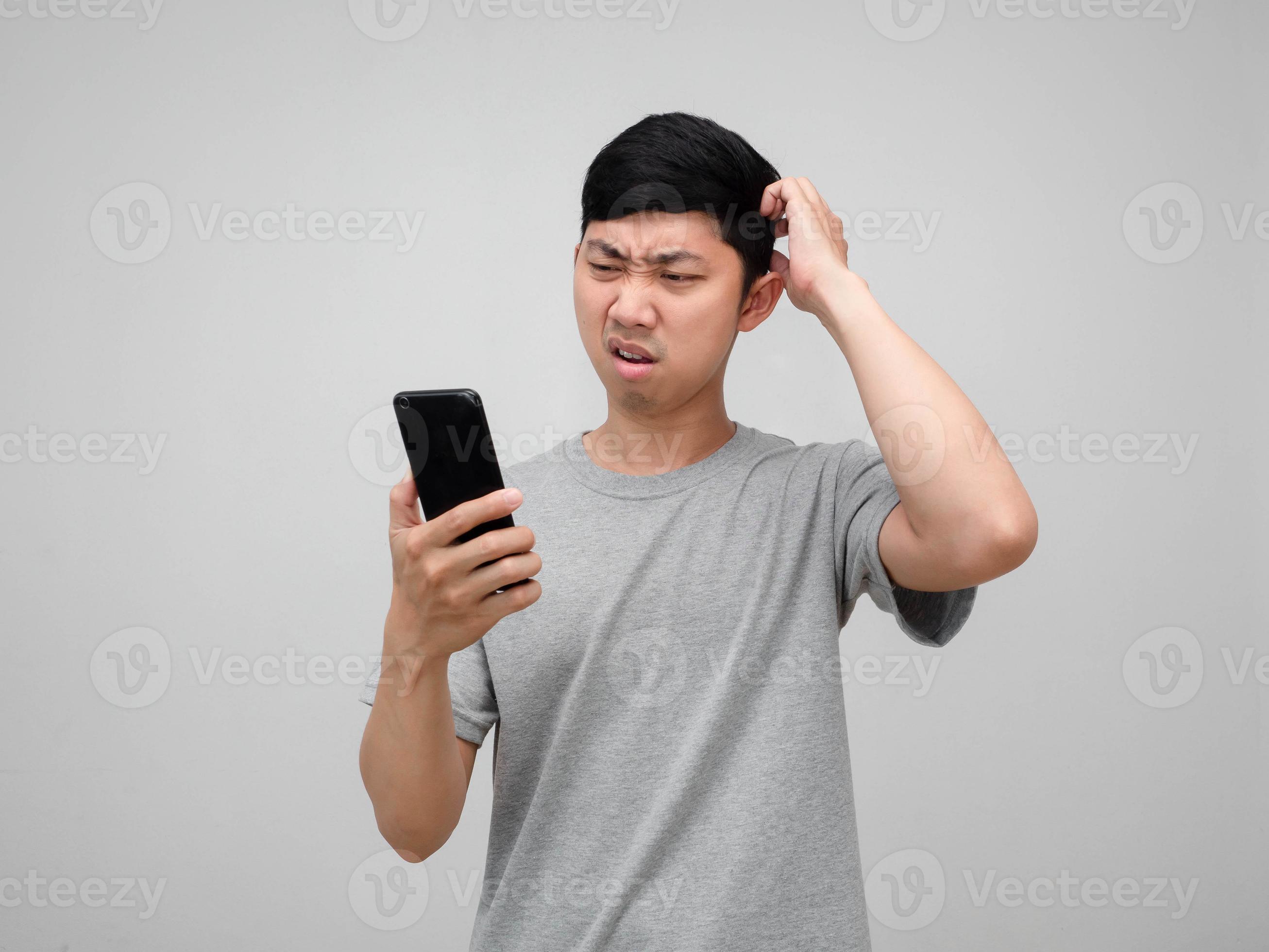 Asian man feels confused gesture scratch head looking at mobile phone