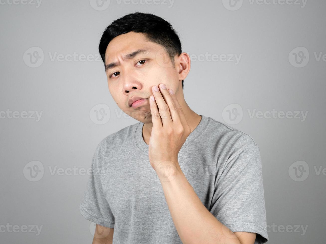 Un hombre asiático de cerca revisando el acné en su rostro se siente preocupado aislado foto