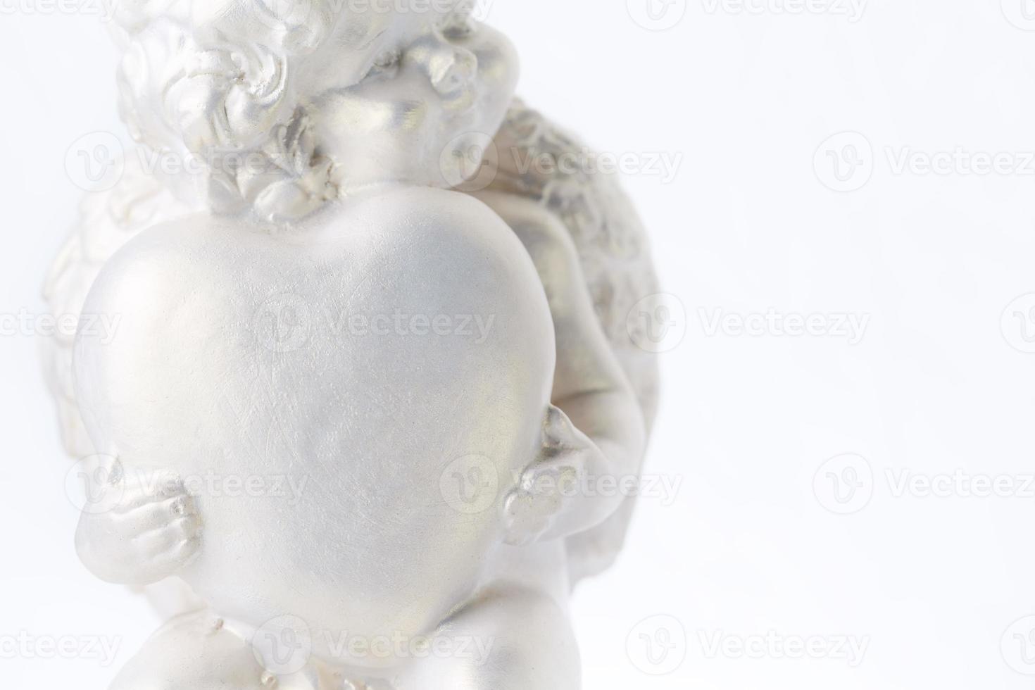 Cherub statue isolated on white background. Angel holds the heart. Love photo
