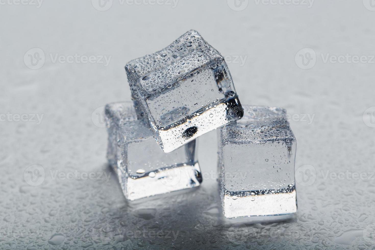 cubos de hielo en forma de pirámide con gotas de agua cerca - en macro sobre un fondo blanco. foto