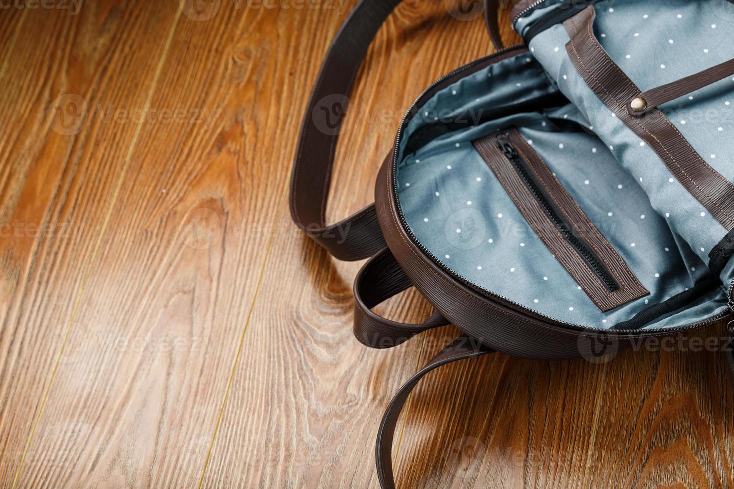 Open empty bag made of handmade genuine leather with elements of locks on a wooden background. photo