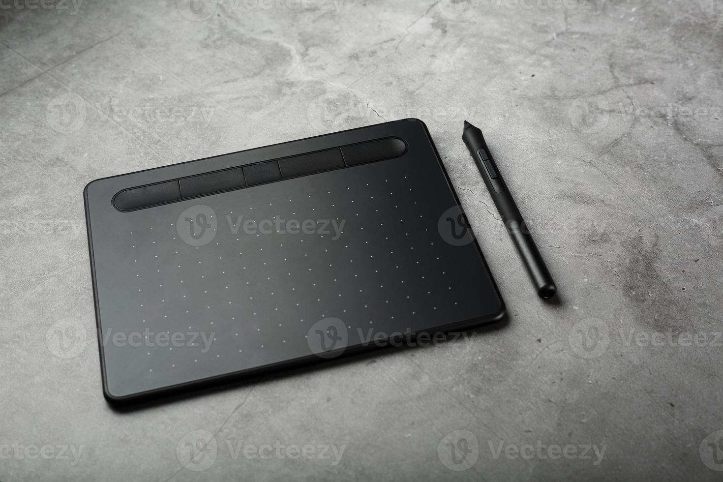 tableta gráfica con un lápiz sobre un fondo textural oscuro, vista superior. gadget para trabajar como diseñador, artista y fotógrafo foto
