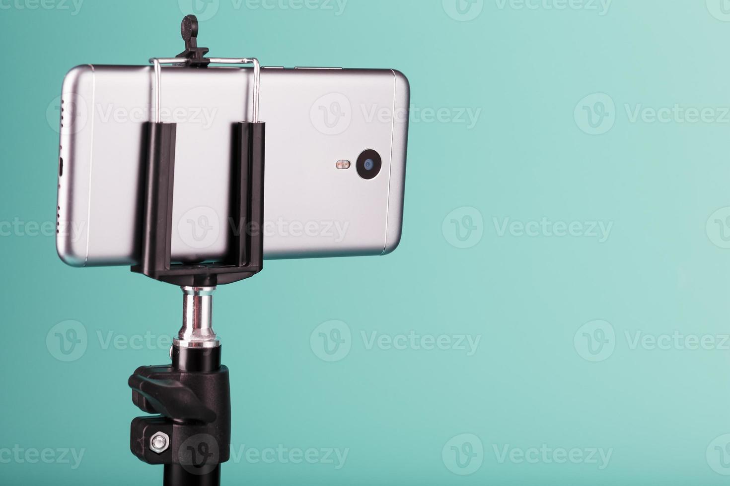 The smartphone is mounted on a tripod as a photo-video camera for a blog on a blue background. Record videos and photos. photo