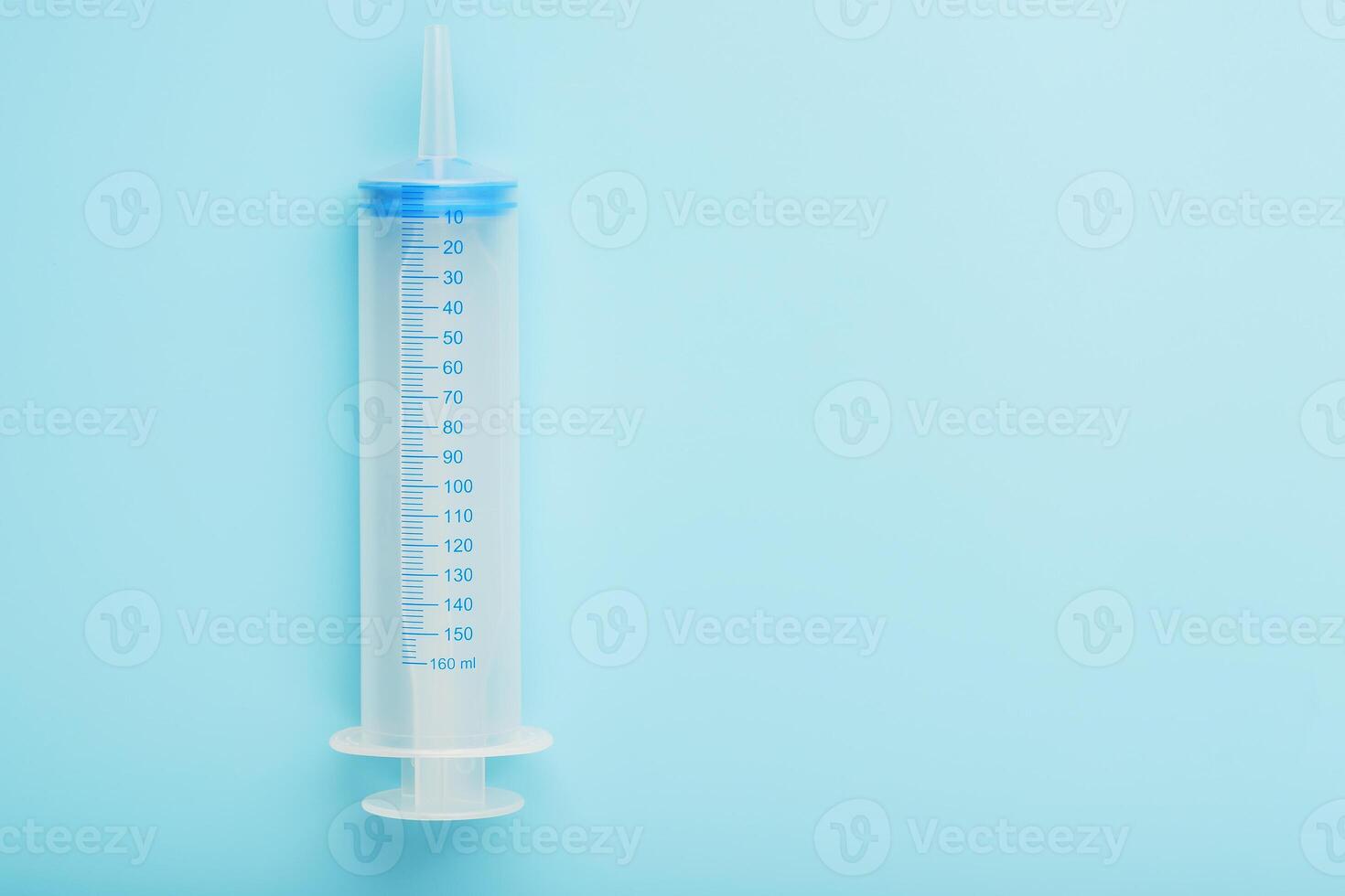 A large medical syringe on a blue background with a scale, a copy of