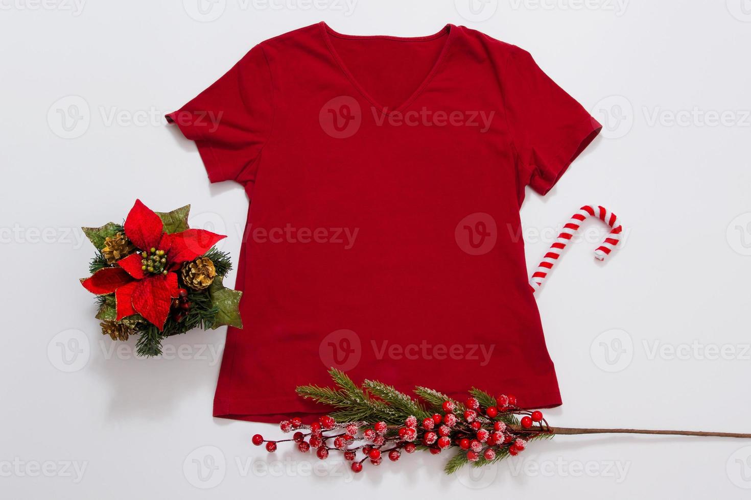 Close up red blank template t shirt with copy space. Christmas Holiday concept. Top view mockup t-shirt. holidays decorations white background. Happy New Year accessories. Xmas outfit. Selective focus photo