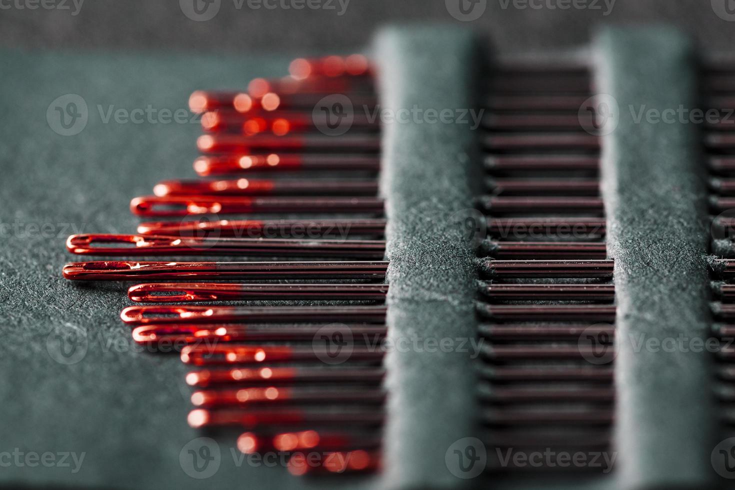 agujas de coser de diferentes tamaños en un conjunto de rojo sobre fondo negro. foto
