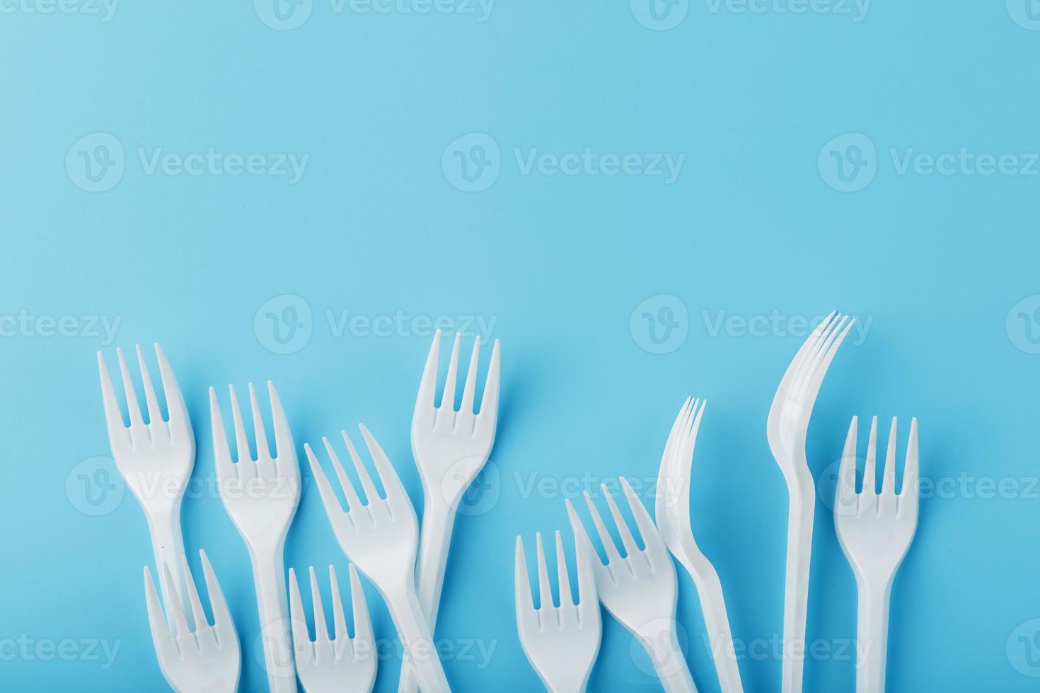 White plastic forks of disposable tableware on a blue background. photo