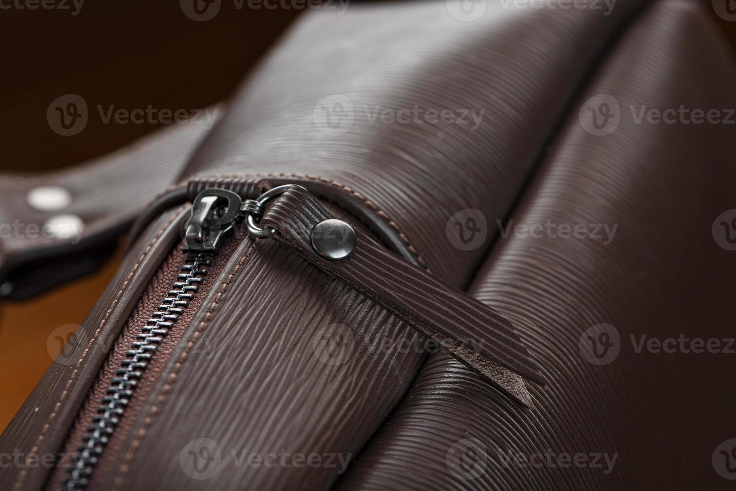 Open empty bag made of handmade genuine leather with elements of locks on a wooden background. photo