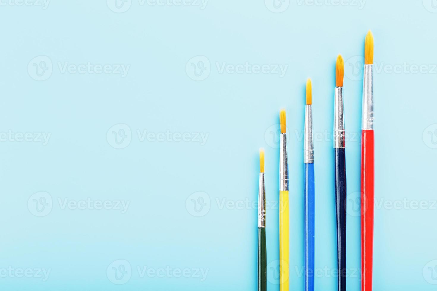 Brushes of different colors for drawing, creativity and art on a blue background. photo